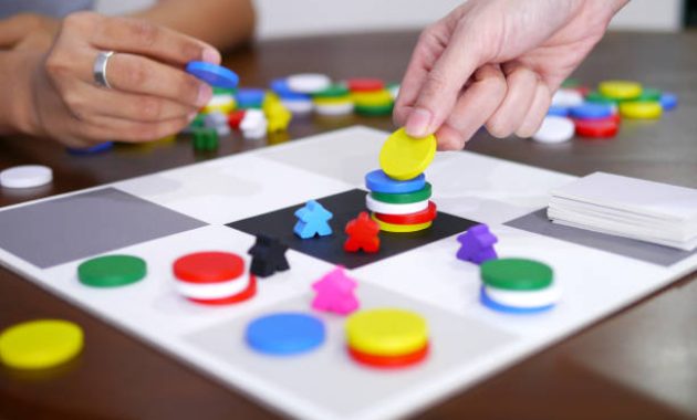 orang-orang bermain permainan papan menyenangkan di atas meja kayu fokus yang dipilih / istockphoto