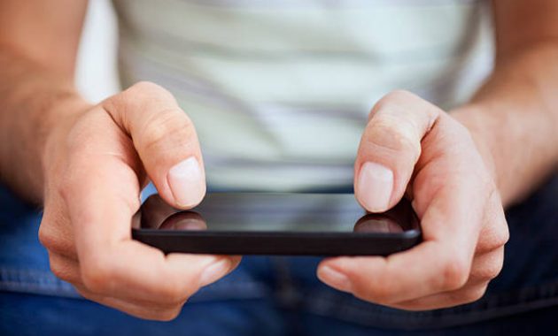 Tangan seorang pria biasa menggunakan smartphone / iStockphoto