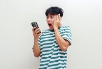 Seorang pria terkejut melihat smartphone / iStockphoto