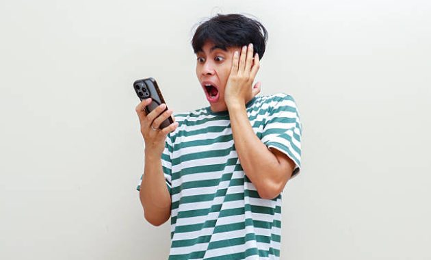 Seorang pria terkejut melihat smartphone / iStockphoto
