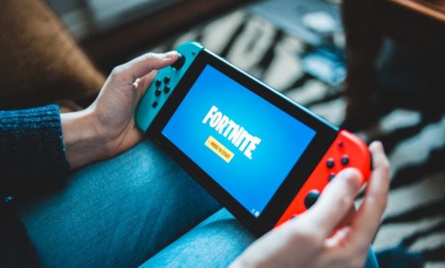 Seseorang yang memegang Nintendo Switch dengan layar permainan Fortnite / pexels-introspectivedsgn