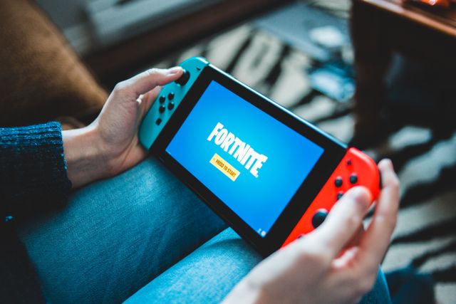 Seseorang yang memegang Nintendo Switch dengan layar permainan Fortnite / pexels-introspectivedsgn